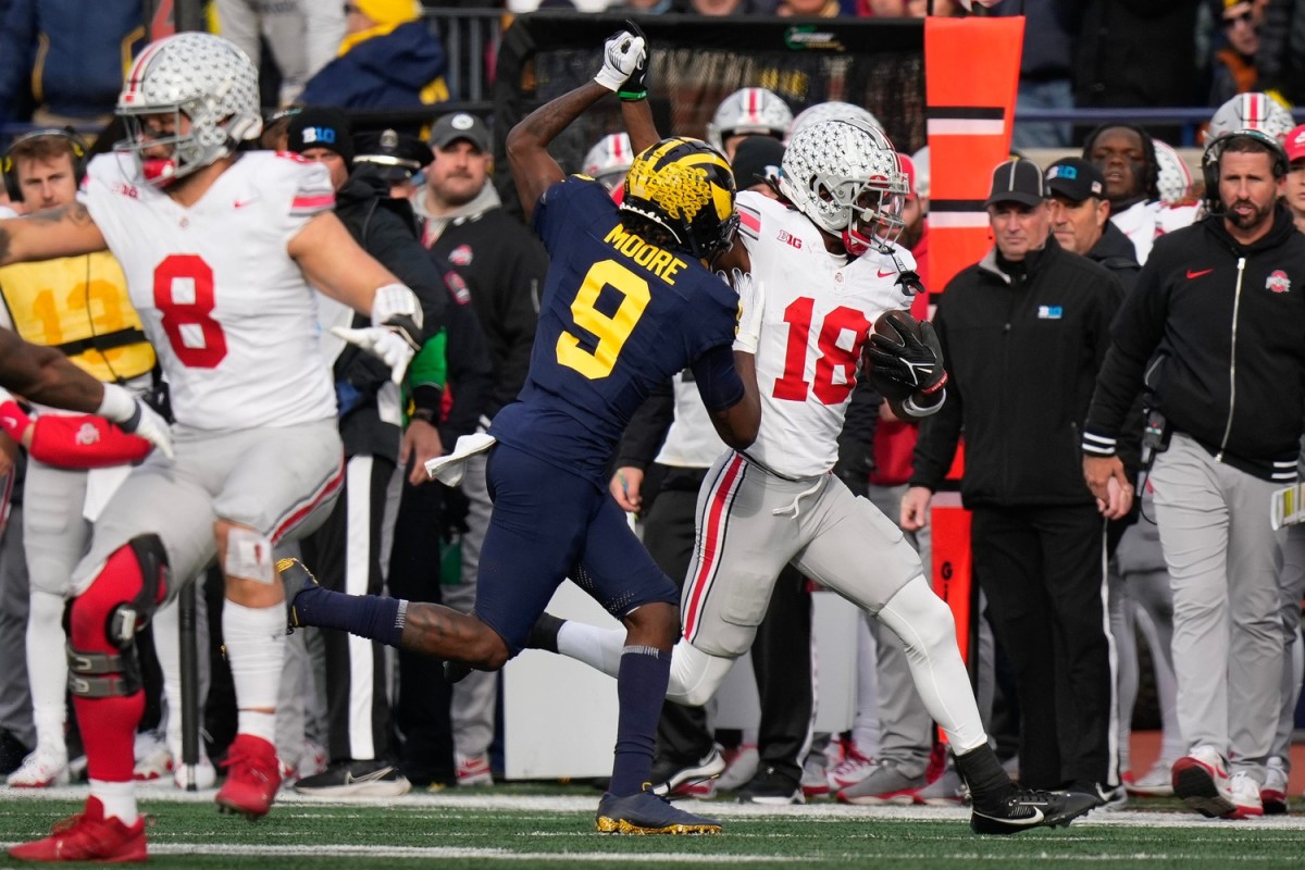 Nov 25, 2023; Ann Arbor, Michigan, USA; Ohio State Buckeyes wide receiver Marvin Harrison Jr. (18) locks hands with Michigan Wolverines defensive back Rod Moore (9) during the NCAA football game at Michigan Stadium. Ohio State lost 30-24.  