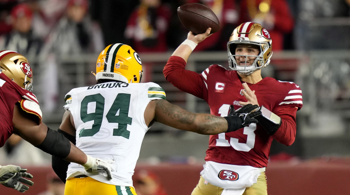 Brock Purdy throws the ball as a Packers player rushes at him