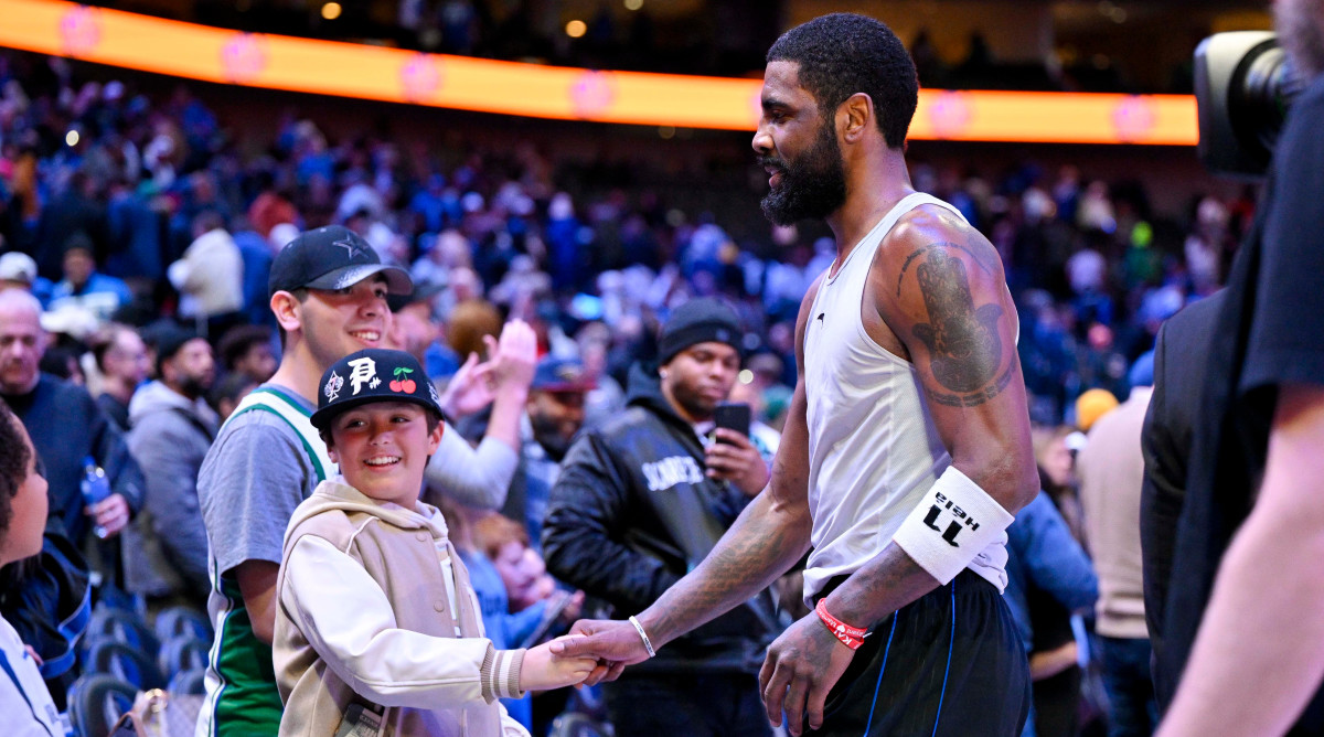 Dallas Mavericks guard Kyrie Irving shakes hands with a fan.