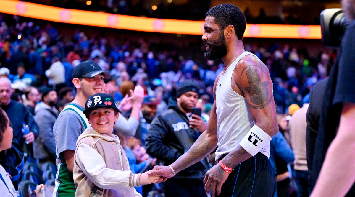 Dallas Mavericks guard Kyrie Irving shakes hands with a fan.
