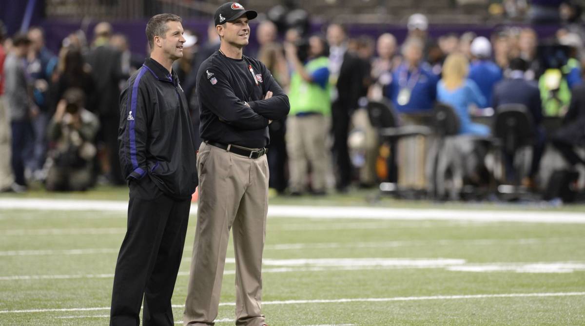 Ravens head coach John Harbaugh and 49ers head coach Jim Harbaugh speak on the field before coaching against each other in the Super Bowl.