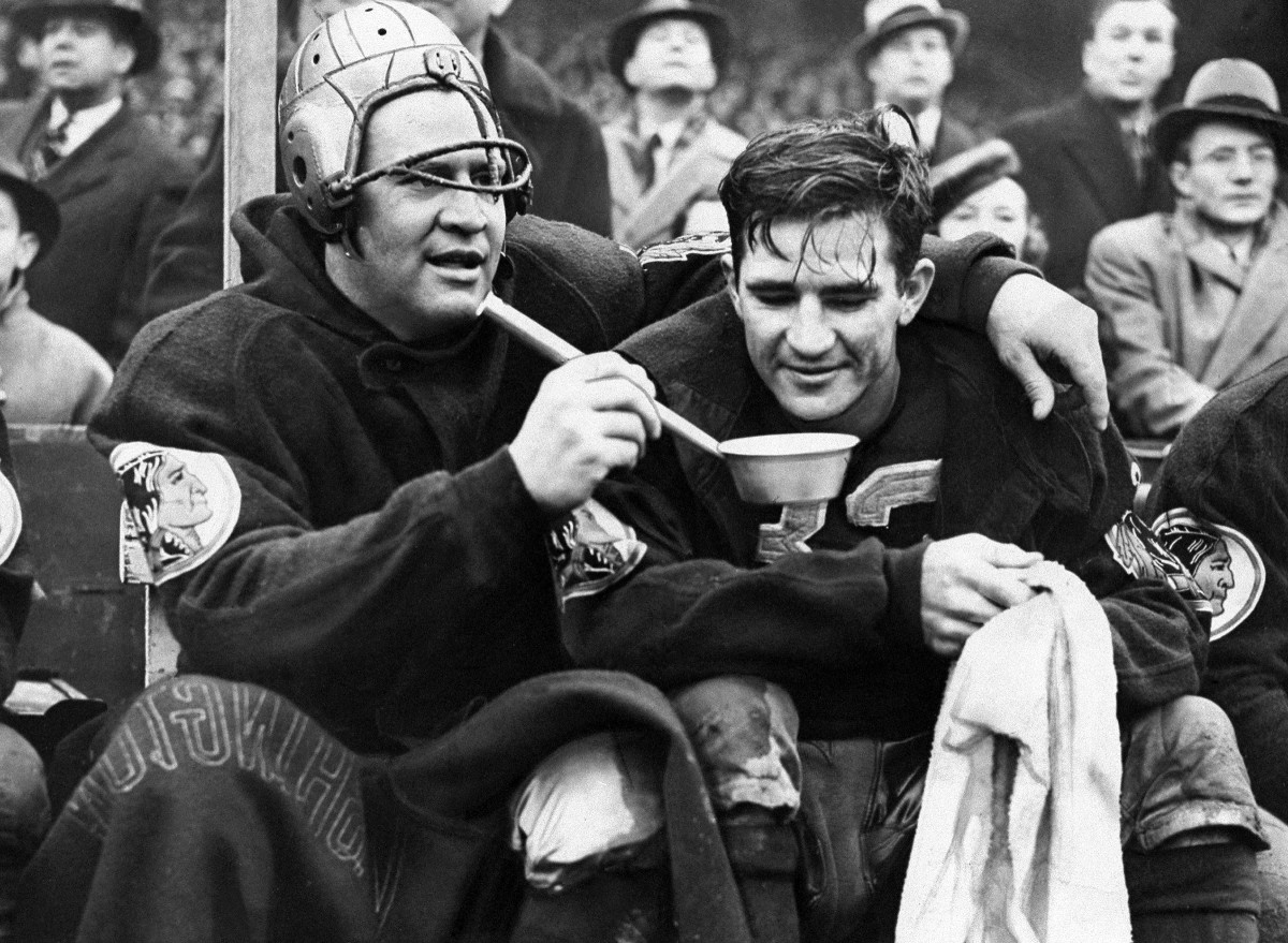 "Slinging" Sammy Baugh is helped to a drink of water by Ernie Pincker