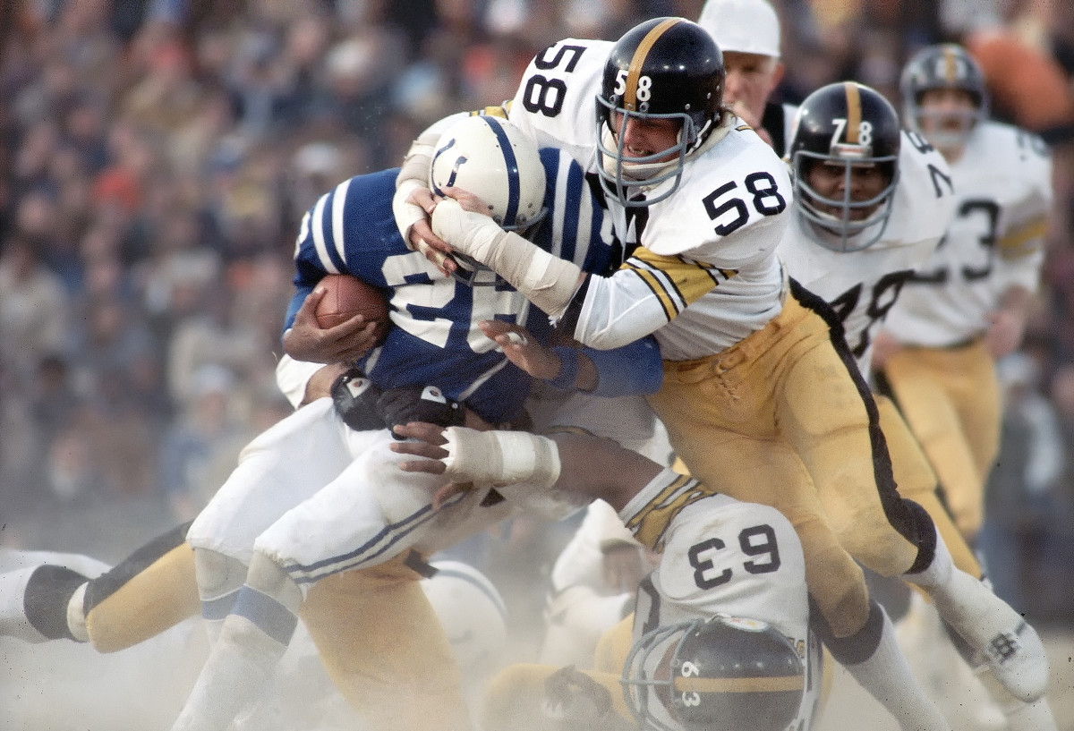 Lydell Mitchell runs with the ball as Steelers’ Jack Lambert and Ernie Holmes tackle him