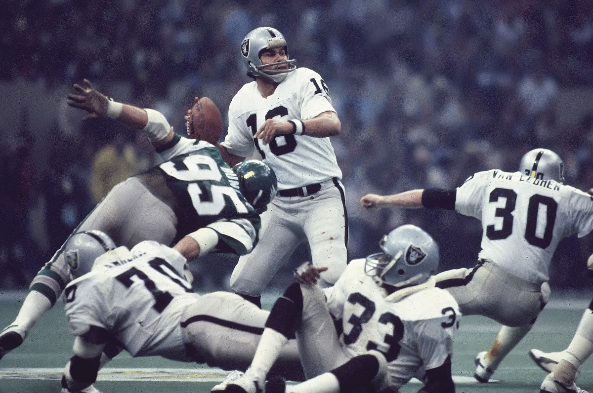 Jim Plunkett goes to throw the ball as other players fall around him