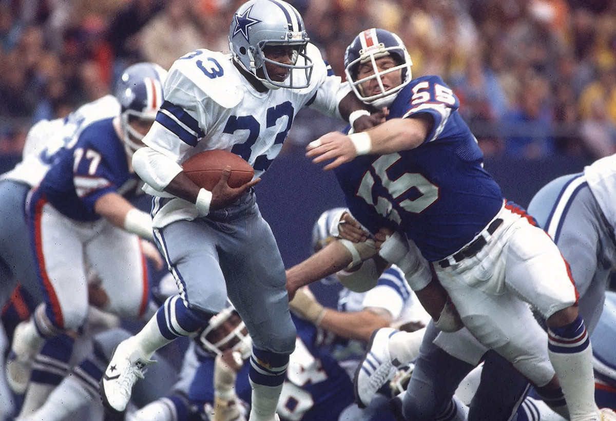 Tony Dorsett runs with the ball as giants players reaches for it