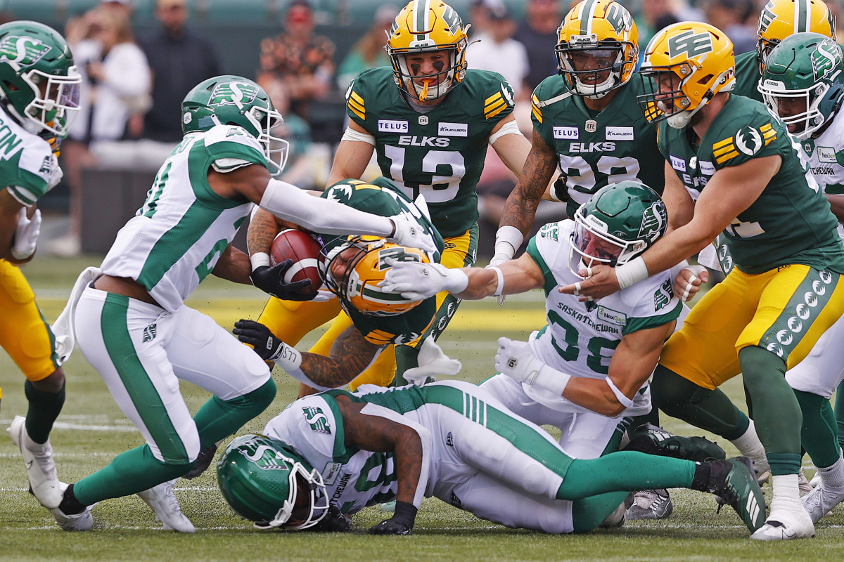 Jun 11, 2023; Edmonton, Alberta, CAN; Saskatchewan Roughriders defensive back Nelson Lokombo (21) and defensive back Jayden Dalke (38) tackle Edmonton Elks wide receiver Dillon Mitchell (17) during the first half at Commonwealth Stadium. Mandatory Credit: Perry Nelson-USA TODAY Sports