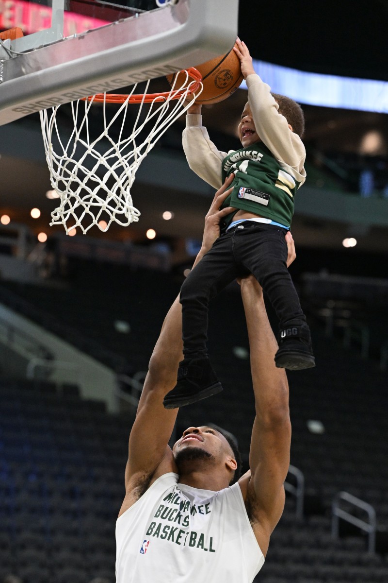 Milwaukee Bucks forward Giannis Antetokounmpo (34) lifts his middle son Maverick up to dunk 